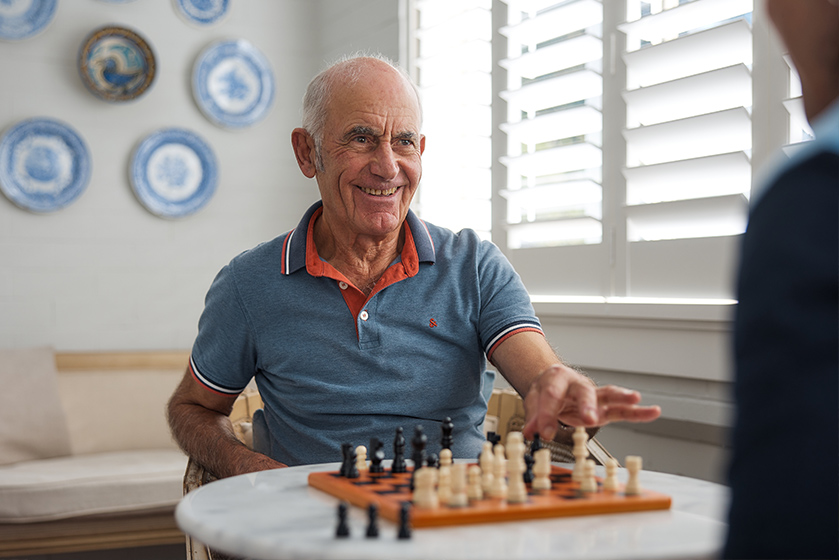 Elder man playing chess with a support worker